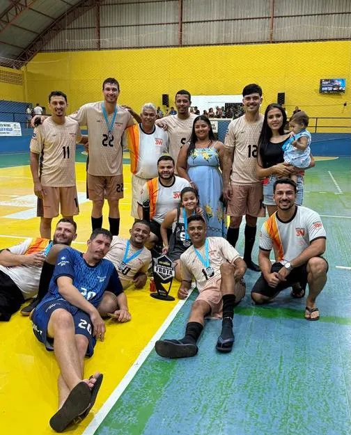 Equipe de futsal adulto comemorando com medalhas na quadra.