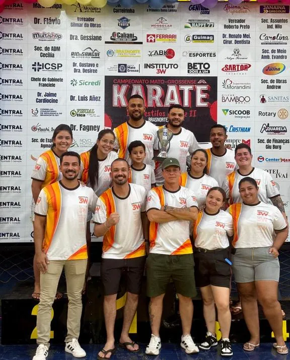 Equipe do Instituto 3W em frente ao painel do campeonato de karatê.